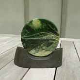 A spectacular, engraved jade disc sculpture. Hand carved in New Zealand from stunning Jade. This is a beautiful disc sculpture carved with a mountain and valley into its face. It is presented with a greywacke beach stone display stand. A beautiful sculptural piece hand carved in New Zealand.